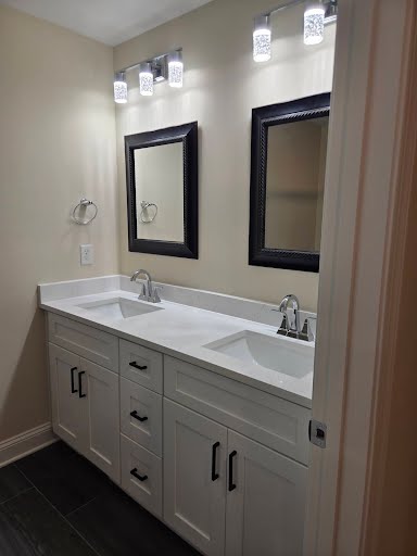 Double sink vanity with quartz top, framed mirrors, and tile floor in the new master bathroom addition