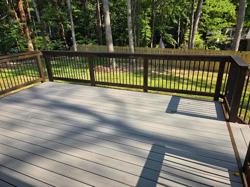 New composite rear deck with dark railing overlooking the fenced backyard