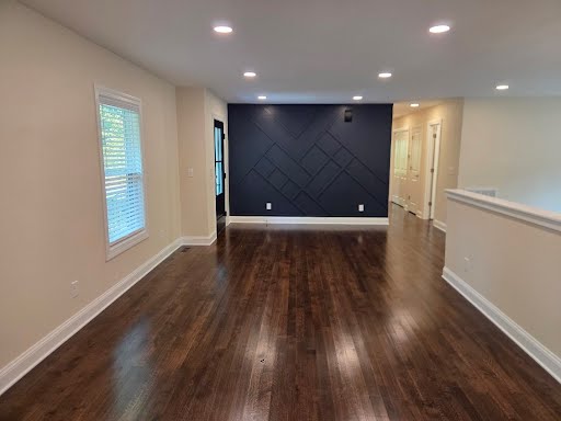 Open living area with refinished hardwood floors and a navy geometric trim accent wall