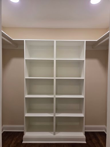 New master closet with white built-in shelving, hanging rods, and recessed lighting