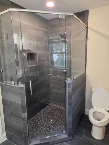 Frameless glass corner shower enclosure with pebble floor in the new master bathroom addition
