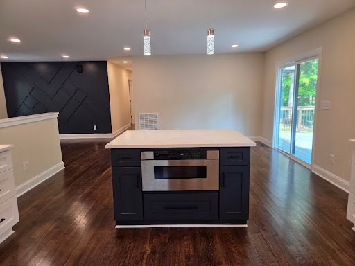 Navy kitchen island with quartz top and built-in microwave drawer opening to the living area
